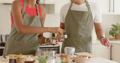 Black couple chopping fresh vegetables together in contemporary kitchen