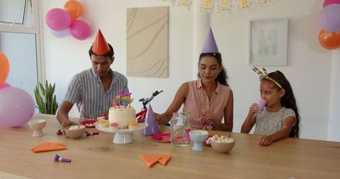 Family celebrating birthday at home with cake and party decorations