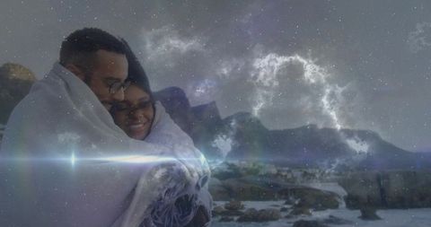 Romantic couple embracing under starry night on rocky shoreline