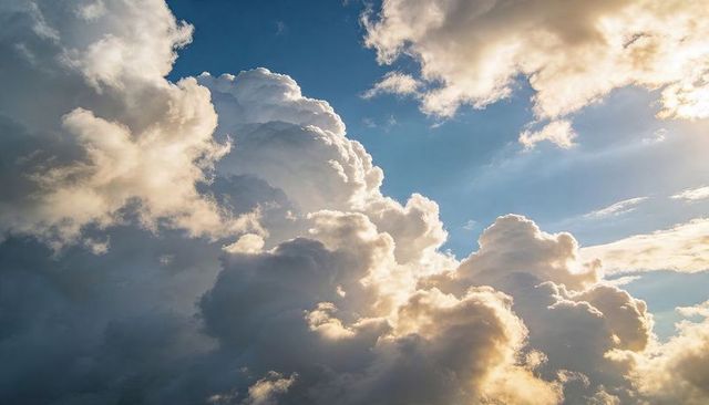 Towering Cumulus Clouds Illuminating Blue Sky with Golden Sunbeams and Crepuscular Rays