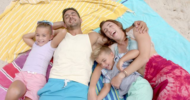 Portrait of happy caucasian family lying on towels at beach. Vacation, free time, summer and family.