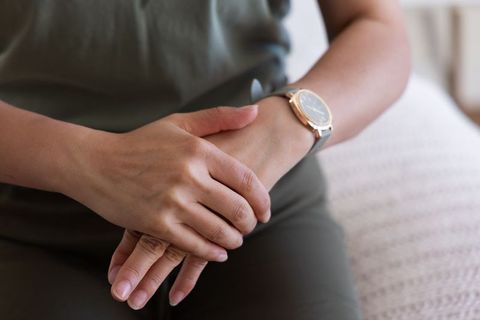 Mature african american woman sitting hands clasped wearing gold watch, cozy lifestyle