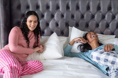 Diverse Friends Laughing in Pajamas on Bed