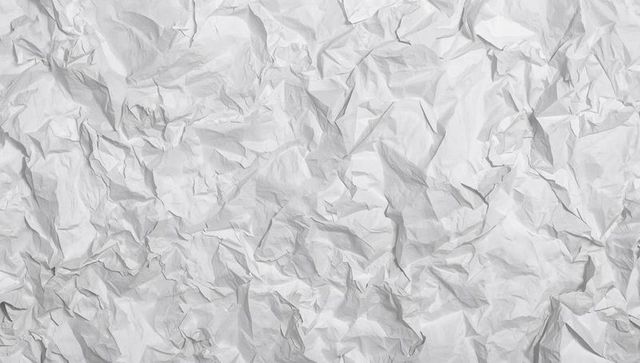 Crumpled white paper texture background showing high-contrast folds and soft shadows