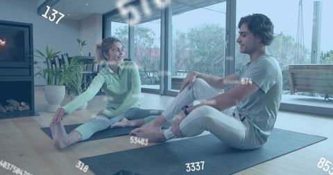 Young couple stretching and practicing seated yoga at home wearing smartwatches