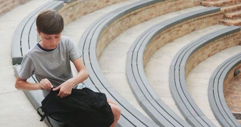 Youthful solitude: boy with backpack in architectural amphitheater