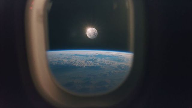 Full moon viewed through spacecraft window with earth horizon
