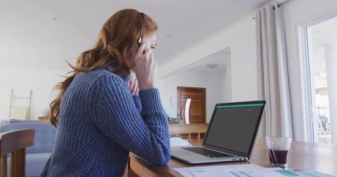 Woman in Home Office Analyzing Reports While Multi-tasking