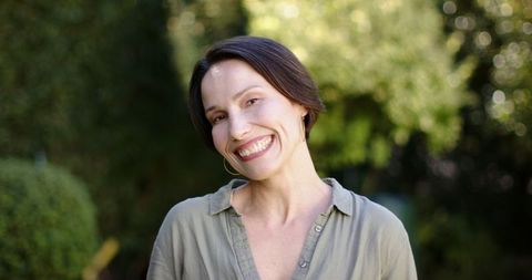 Smiling Woman Outdoors in Green Shirt Embracing Nature