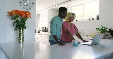 African American Couple Smiling in Modern Kitchen with Laptop