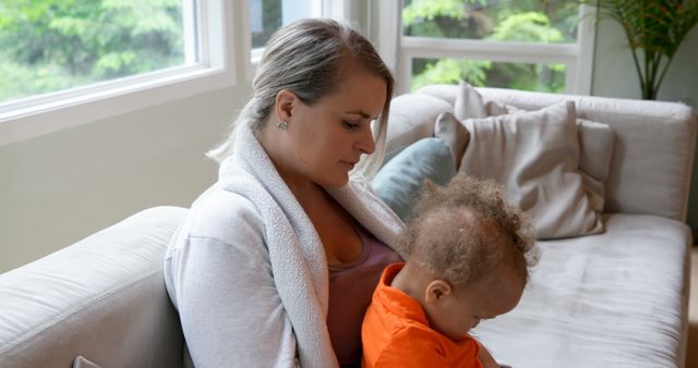 Mother Cuddling Baby on Sofa in Bright Living Room - Download Free Stock Images Pikwizard.com