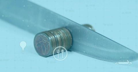 Cutting coins with knife symbolizing financial challenges