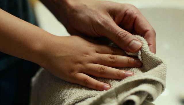 Holding child hand drying with towel at sink closeup conveying care and warmth