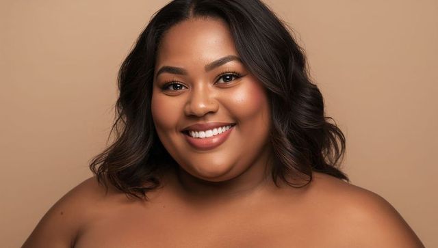 Radiant african american woman smiling bare shoulders beauty headshot warm skin tone