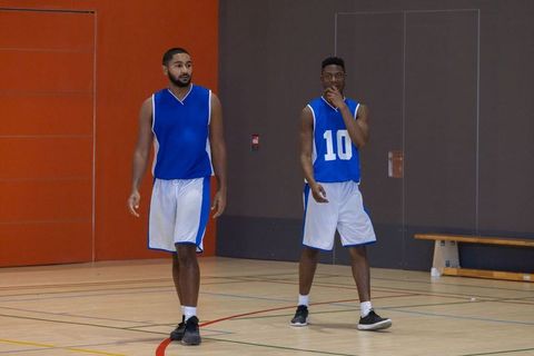 Teammates Walking on Basketball Court in Sports Jerseys