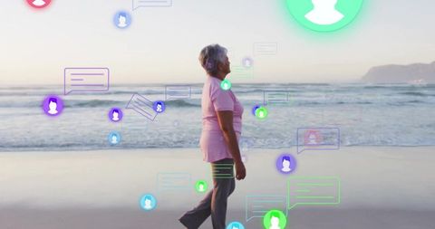 Senior woman walking along beach with floating chat bubbles and digital social connections