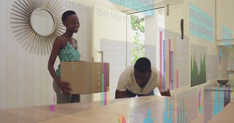 Young couple moving into modern home while reviewing projected charts and data overlay