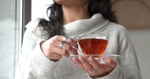 Cozy Morning Ritual with Elegantly Held Amber Tea by Window