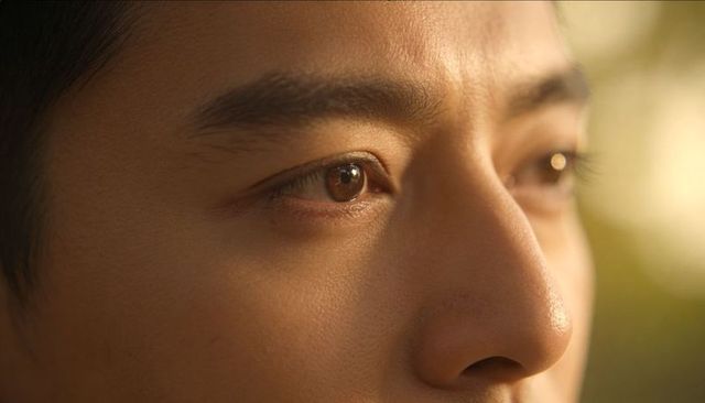 Sunlit asian man closeup capturing warm golden-hour eye detail and skin texture