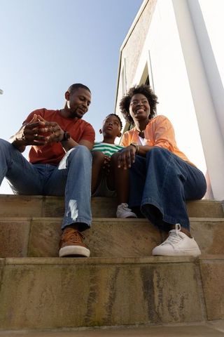 African american family sitting on sunlit steps enjoying casual outdoor togetherness