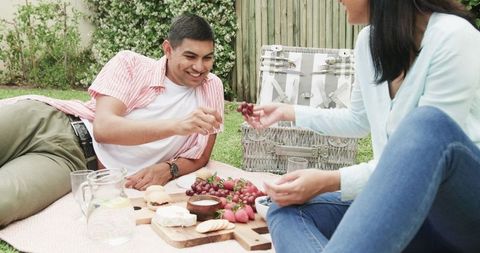 Couple Relishing Outdoor Picnic with Snacks and Drinks on Blanket