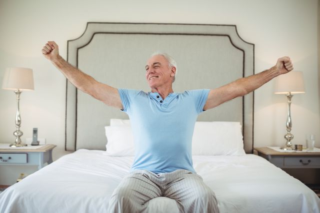 Senior man waking up in bed and stretching his arms 