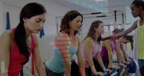 Instructor Adjusting Alignment in Group Reformer Pilates Class for Women in Fitness Studio