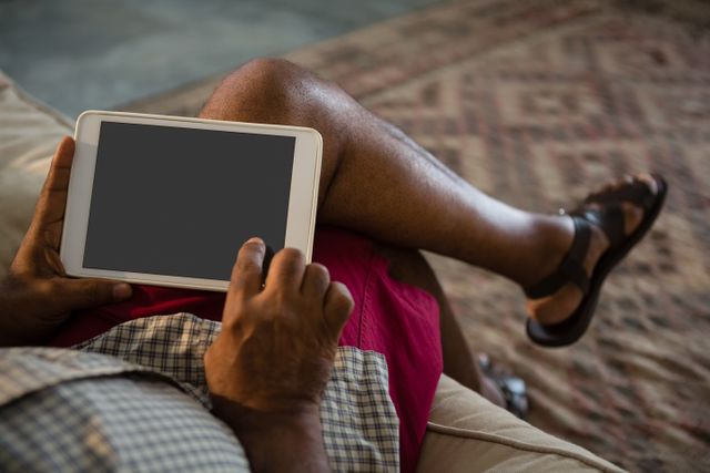 Low-section of senior man using digital tablet in the living room at home