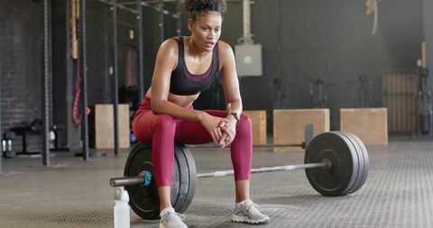 Female athlete resting after heavy deadlift, showing strength, focus and endurance in gym