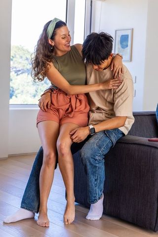 Smiling diverse couple sharing affectionate moment on sofa in sunlit modern apartment