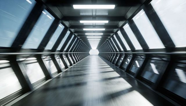 Futuristic glass and steel skybridge corridor leading toward bright hexagonal opening
