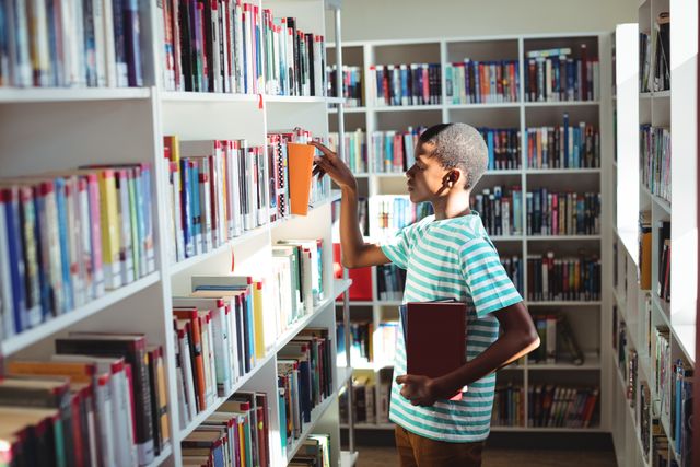 Schoolboy selecting book in library at school