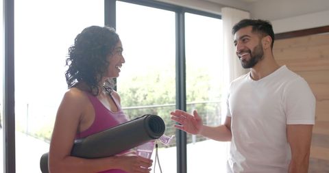 Joyful Couple with Yoga Mats Sharing a High Five at Home