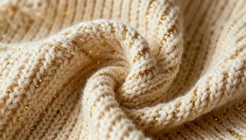 Shimmering cream ribbed knit with gold thread accents, cozy luxury textile macro