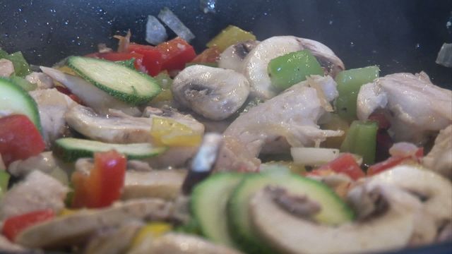 Close-up view of vibrant mixed vegetables including zucchini, mushrooms, and bell peppers being stir-fried in a pan. Ideal for use in cooking blogs, recipe websites, and articles promoting healthy eating and nutritious recipes.