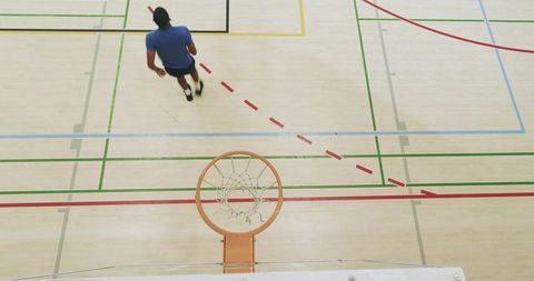 Overhead view basketball player dribbling at half-court during indoor team training