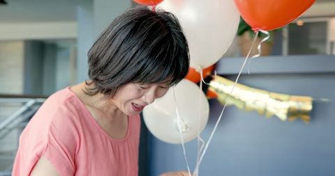 Senior Woman Smiling with Balloons at Celebration Party