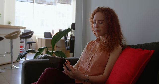 Red-Haired Woman Relaxing on Sofa with Tablet in Modern Room - Download Free Stock Images Pikwizard.com