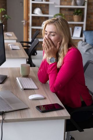 Office worker yawning at modern workspace