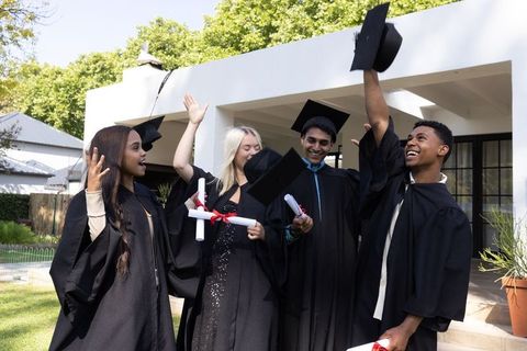 Diverse Graduates Celebrating Outdoors with Caps in Air
