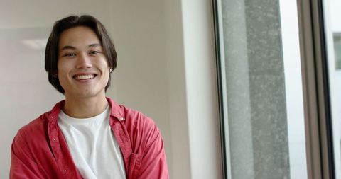 Smiling Young Man in Casual Red Shirt in Modern Bright Room