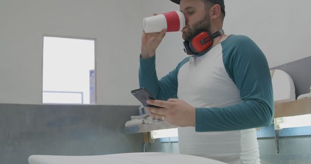 Man Drinking Coffee and Using Smartphone in Workshop - Download Free Stock Images Pikwizard.com