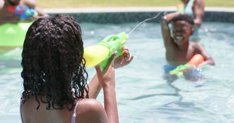 Children Playing with Water Guns in Summer Pool