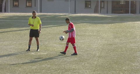 Referee observing young soccer player in action
