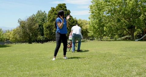 Family Teaching Child Bike Riding with Training Wheels Outdoors