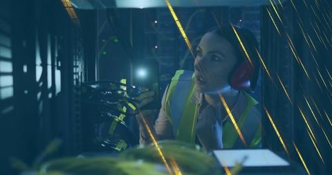Engineer in illuminated server room examining network equipment