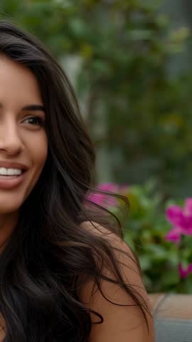 Close-up smiling woman responding in garden with pink blossoms conversational vertical video