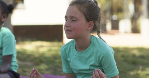 Schoolyard mindfulness: diverse girls practicing meditation on yoga mats in sunny park