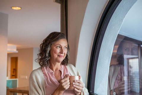Mature Woman Holding Mug Enjoying Quiet Moment by Window