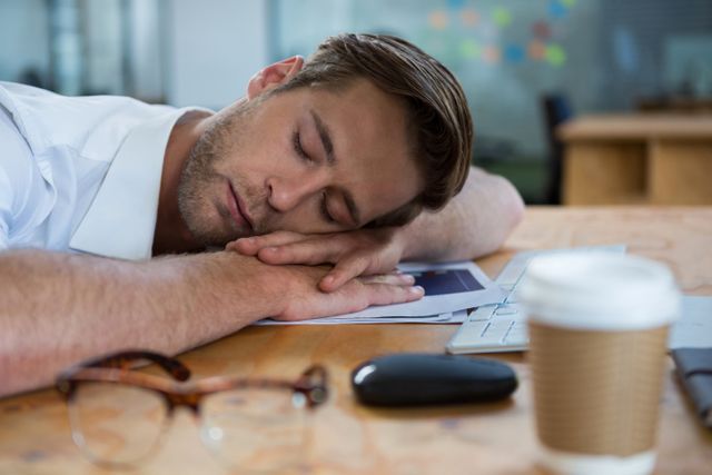 Male graphic designer sleeping at desk in office